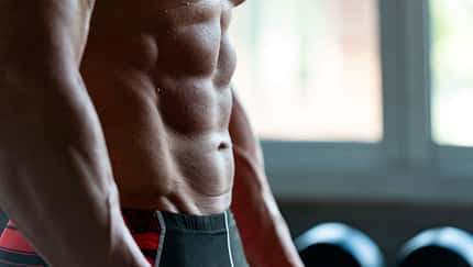 Die seitliche Ansicht von dem Sixpack eines trainierten Mannes im Gym