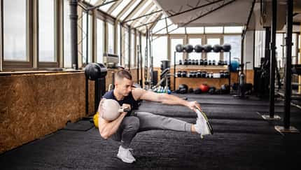 Junger Mann führt in einem Fitnessstudio eine single-leg-Übung mit einem Kettleball aus