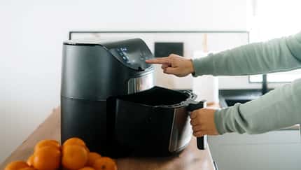 Eine männliche Hand, die einen Airfryer bedient Eine männliche Hand, die einen Airfryer bedient