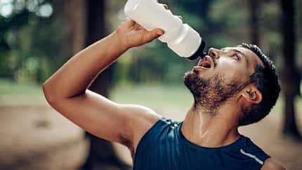Männlicher Läufer macht im Wald eine Pause, um zu trinken Männlicher Läufer macht im Wald eine Pause, um zu trinken