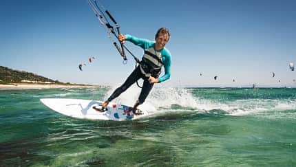 Mann beim Kitesurfen auf dem Meer, im Hintergrund sind viele weitere Kitesurfer Mann beim Kitesurfen auf dem Meer, im Hintergrund sind viele weitere Kitesurfer