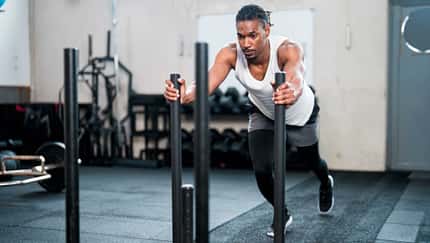 Sportler schiebt einen gewichteten Schlitten in einem Fitnessstudio Sportler schiebt einen gewichteten Schlitten in einem Fitnessstudio