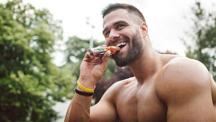 Muskulöser Mann, der einen Proteinriegel isst