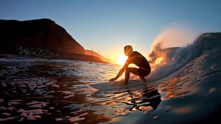 Surfer surft eine Welle im Sonnenuntergang