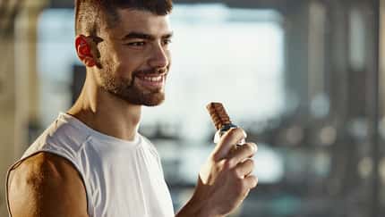 Ein glücklicher Sportler isst einen Proteinriegel Ein glücklicher Sportler isst einen Proteinriegel