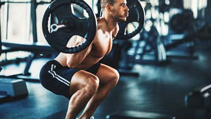 Ein Mann führt Kniebeugen mit einer Langhantel aus im Gym Ein Mann führt Kniebeugen mit einer Langhantel aus im Gym