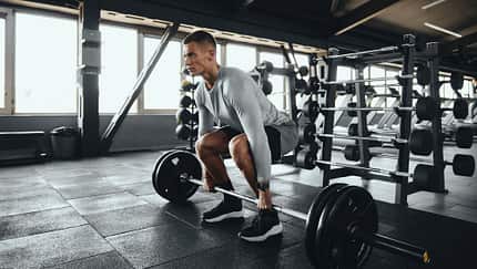 Ein Mann führt Deadlifts aus mit einer Langhantel im Gym Ein Mann führt Deadlifts aus mit einer Langhantel im Gym