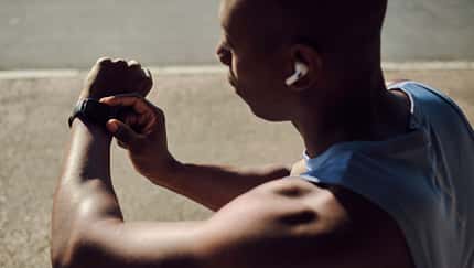 Ein Mann, der sich vom Training erholt und auf seinen Fitness-Tracker schaut