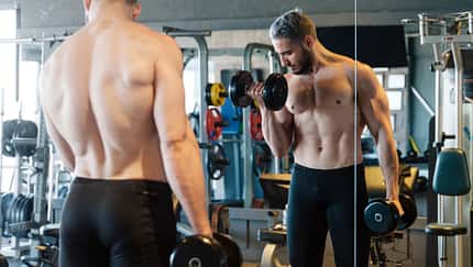Mann steht beim Gewichtheben im Gym vorm Spiegel Mann steht beim Gewichtheben im Gym vorm Spiegel
