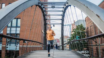 Ein Mann läuft in der Stadt auf einer Brücke Ein Mann läuft in der Stadt auf einer Brücke