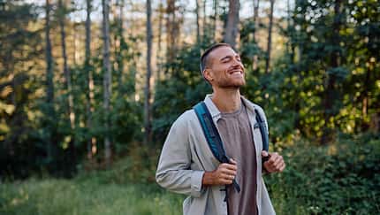 Young male hiker enjoying fresh air in forest during trekking day Young male hiker enjoying fresh air in forest during trekking day