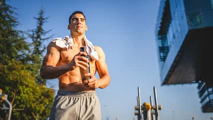 Ein trainierter, oberkörperfreier Mann hält einen Shaker in der Hand Ein trainierter, oberkörperfreier Mann hält einen Shaker in der Hand