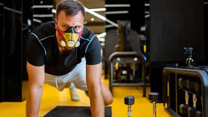 Mann trainiert mit einer Höhentrainigsmaske im Fitnessstudio