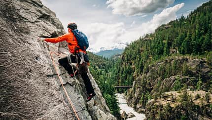 Ein Mann klettert vor einer Naturkulisse Ein Mann klettert vor einer Naturkulisse