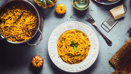 Ein Küchentisch mit Spaghetti und Kürbis