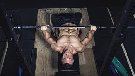 Physical athlete doing barbell bench presses