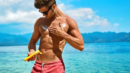 Mann cremt sich mit Sonnencreme ein