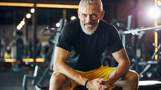 Sportsman with a happy smile sitting on the weight bench