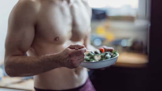 Ein trainierter Mann isst einen Salat nach dem Training