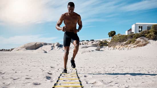 A handsome young african american male athlete working out on the beach. Dedicated black man exercising with sports equipment outside on the sand. Committed to a healthy lifestyle and getting fit
