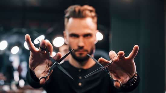 Mann mit Schere vor dem Gesicht