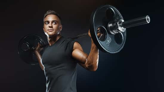 Muscular man training squats with barbells over head