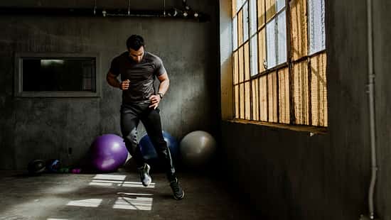 Sportlicher Mann, der in einem Fitnessstudio einen Seitwärtssprung macht