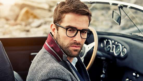 Ein Mann mit Brille hinterm Steuer im Auto