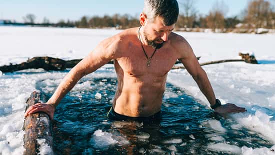 Courageous man taking an ice bath in frozen lake during winter