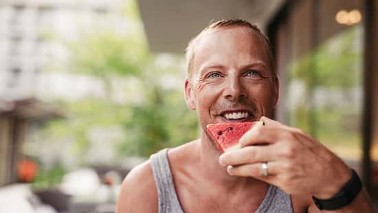 Ein Mann beißt glücklich in eine Wassermelone
