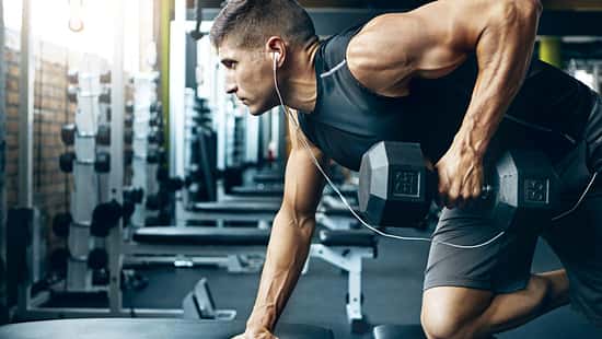 Ein trainierter Mann im Gym, der Rudern mit einer Kurzhantel an einer Bank macht