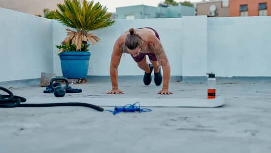 Ein Mann macht draußen oberkörperfrei Burpees 