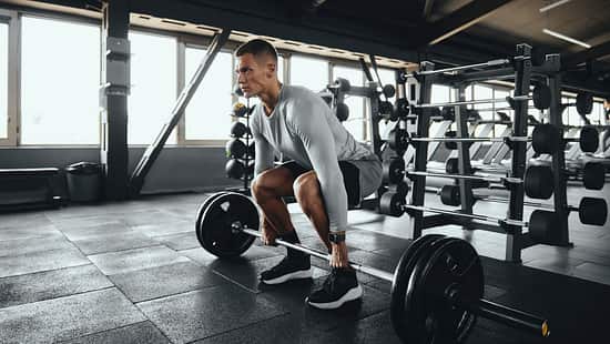 Ein Mann führt Deadlifts aus mit einer Langhantel im Gym