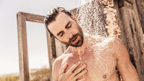 Ein junger Mann nimmt draußen eine kalte Dusche