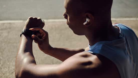 Ein Mann, der sich vom Training erholt und auf seinen Fitness-Tracker schaut