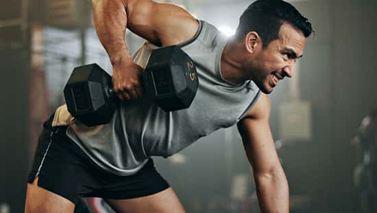 Ein trainierter Mann macht Rudern im Gym mit einer Kurzhantel