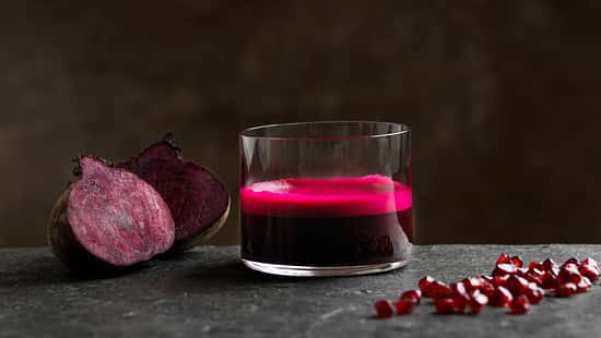 Ein Glas Rote Beete Saft vor dunklem Hintergrund