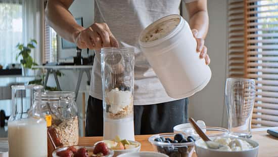 Ein junger Mann bereitet sich im Mixer einen Proteinshake zu