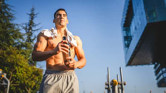 Ein trainierter, oberkörperfreier Mann hält einen Shaker in der Hand 