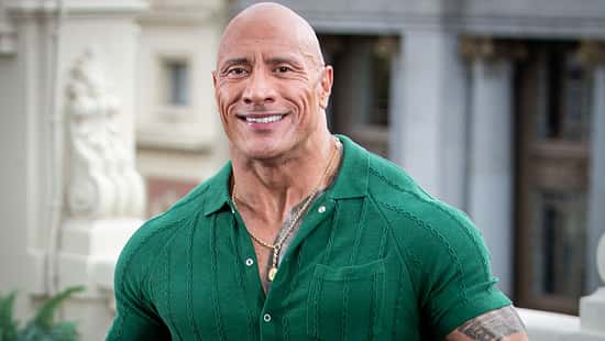 Dwayne Johnson lächelt im grünen Oberteil in die Kamera