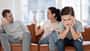 Man sieht im Vordergrund einen kleinen Jungen, der genervt guckt, im Hintergrund sitzen seine Mutter und sein Vater auf dem Sofa und diskutieren.