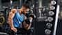 Bodybuilder,Pumping,His,Biceps,With,Dumbbell,In,Gym,,Empty,Space