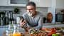 Ein Mann schaut auf sein Handy und kocht gesund