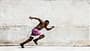 Mann in pinker Shorts sprintet vor einer hellen Betonwand Mann in pinker Shorts sprintet vor einer hellen Betonwand