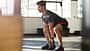 Mann macht eine Kniebeuge mit einem Kettleball Mann macht eine Kniebeuge mit einem Kettleball