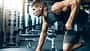 Ein trainierter Mann im Gym, der Rudern mit einer Kurzhantel an einer Bank macht Ein trainierter Mann im Gym, der Rudern mit einer Kurzhantel an einer Bank macht