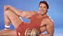 Arnold Schwarzenegger posiert vor einem blauen Hintergrund in einem roten Sportoutfit mit einer Kurzhantel Arnold Schwarzenegger posiert vor einem blauen Hintergrund in einem roten Sportoutfit mit einer Kurzhantel