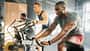 Zwei Männer und eine Frau trainieren im Gym auf dem Fahrrad Zwei Männer und eine Frau trainieren im Gym auf dem Fahrrad