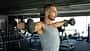 Mann trainiert Schultern mit Kurzhanteln im Gym Mann trainiert Schultern mit Kurzhanteln im Gym