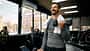 Junger Sportler, der mit Kurzhanteln im Fitnessstudio trainiert